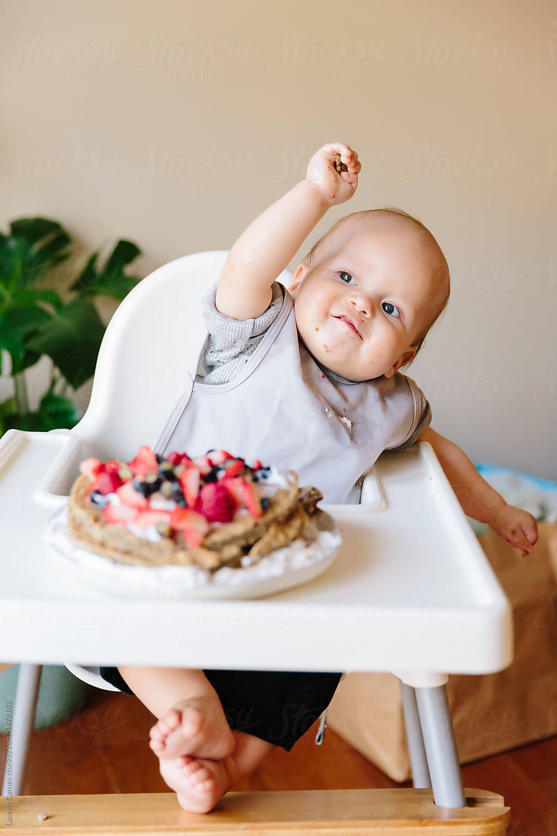 Baby eating fruit smash cake on first birthday