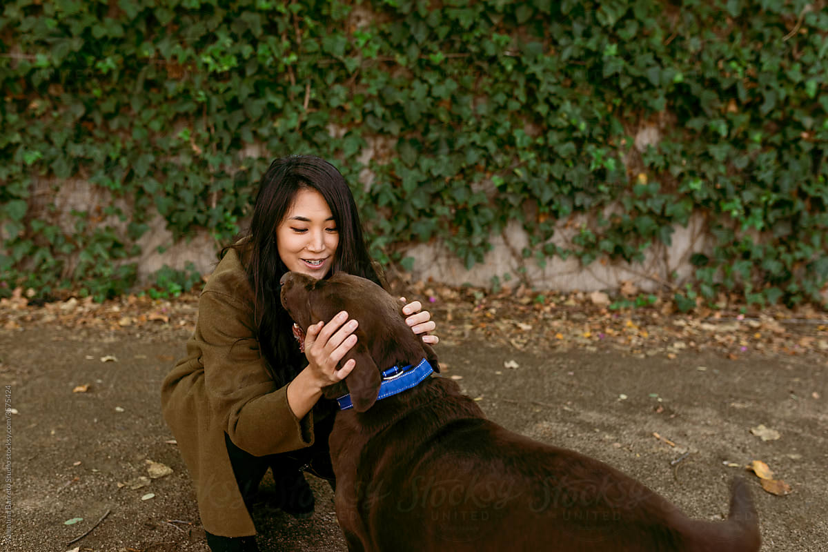asian woman playing with her dog in the park