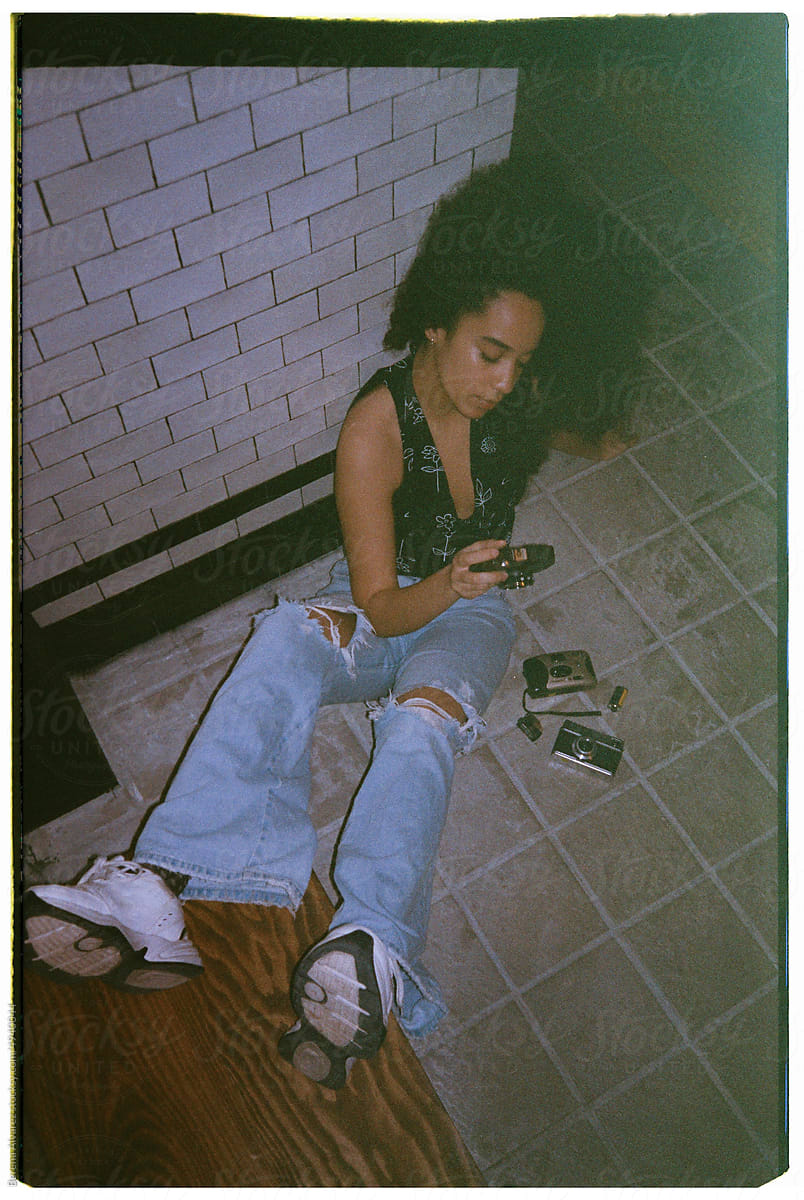 beautiful afro woman with vintage photo cameras sitting on the floor