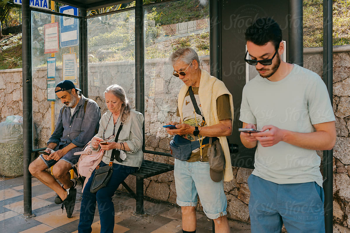 People waiting in bus stop checking their smartphones