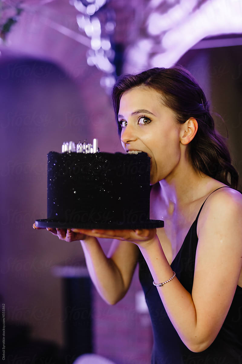 Elegant woman bitting and enjoying delicious cake during party