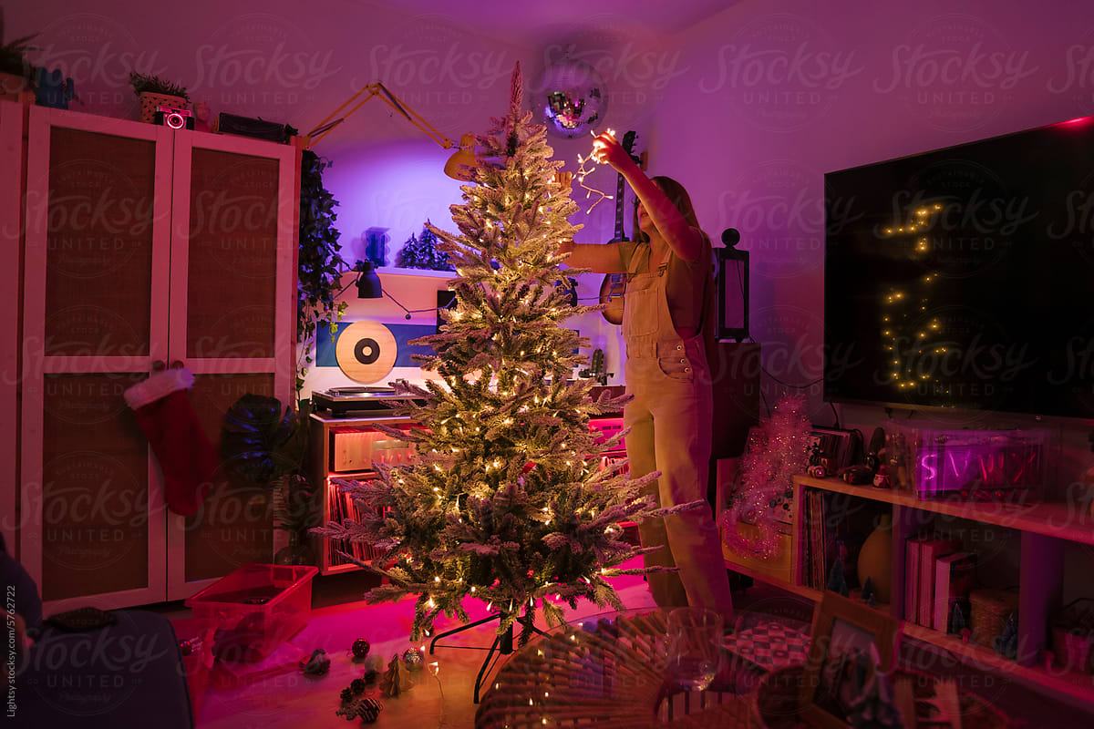 A woman decorating a Christmas tree in a living room