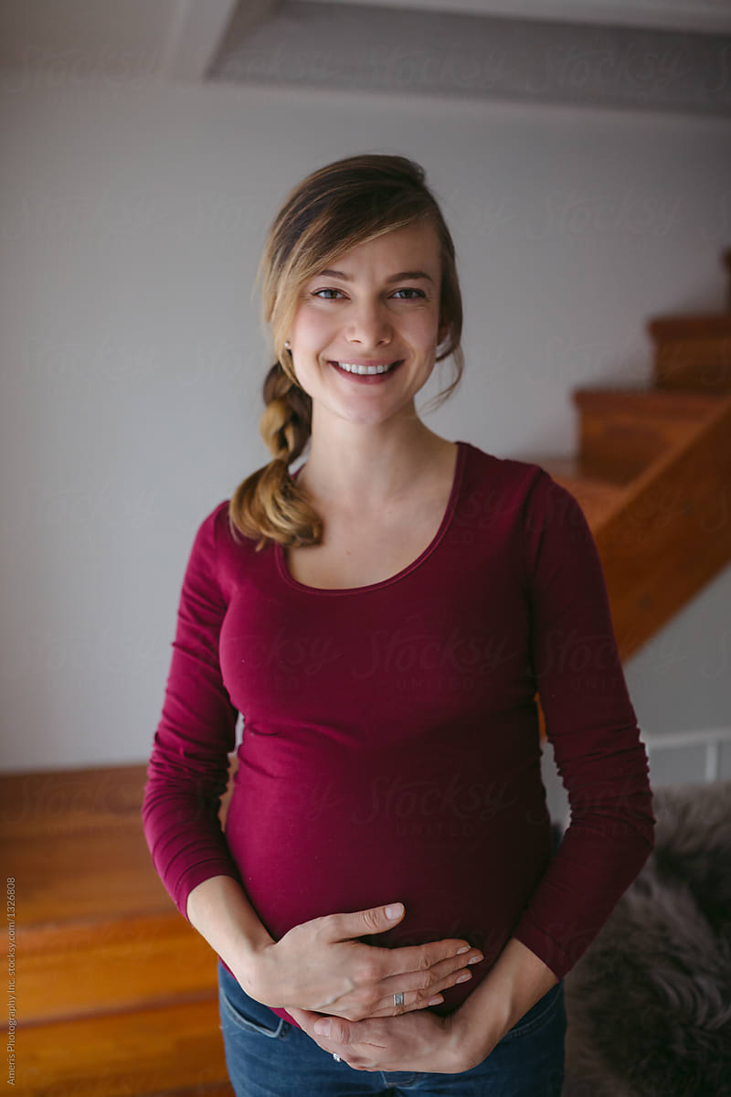 Content pregnant woman at home smiling at camera