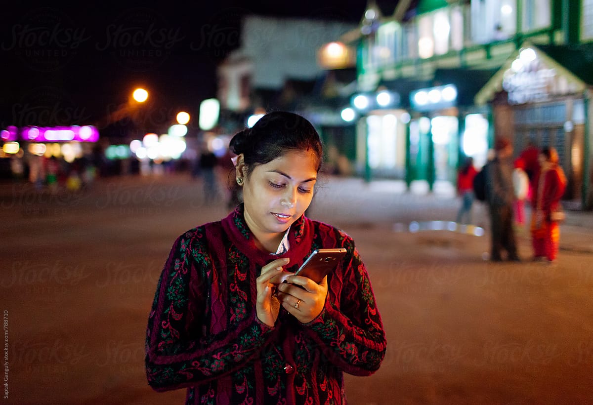 Young woman using mobile phone in the street at night