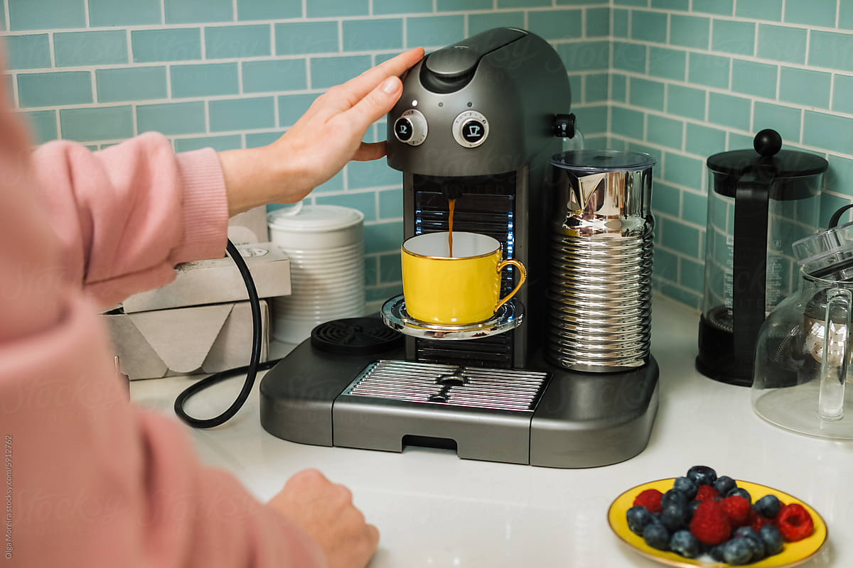 Anonymous woman preparing a cup of coffee in coffee machine
