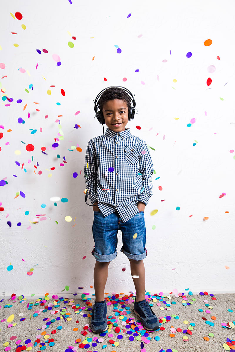 Little boy listening music whilst confetti falls from above.