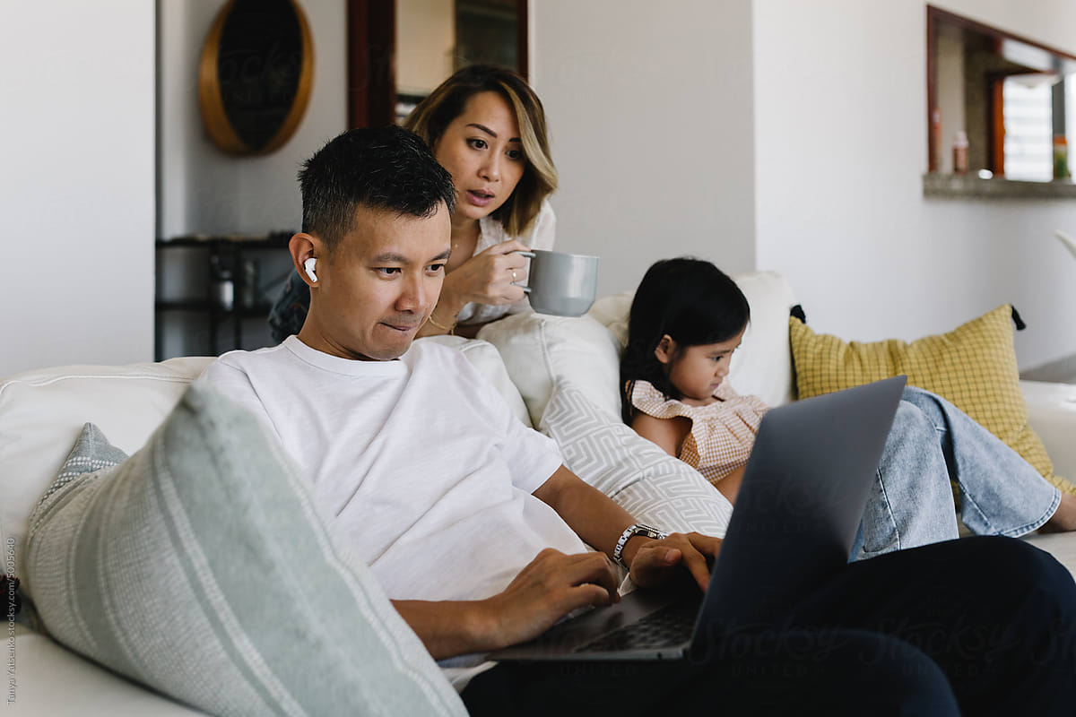 Family of three on the couch in a living room with gadgets