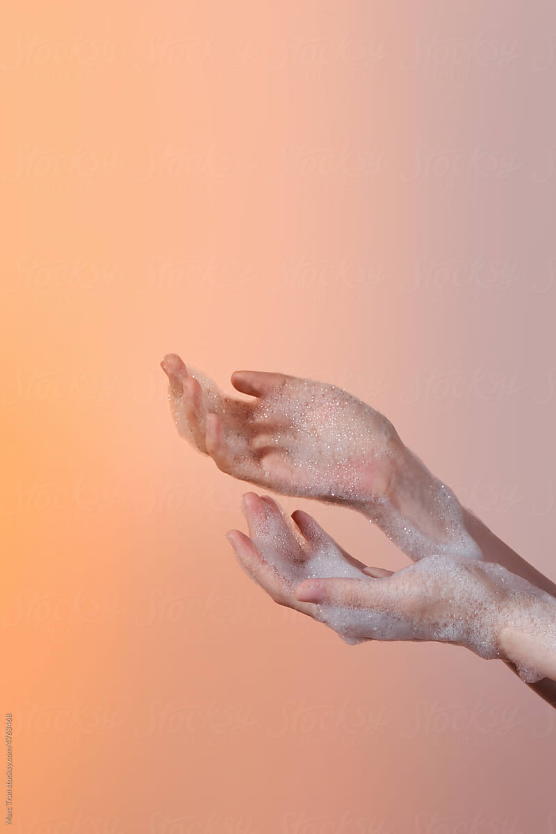 Hands washing gesture with foaming hand soap on color background.