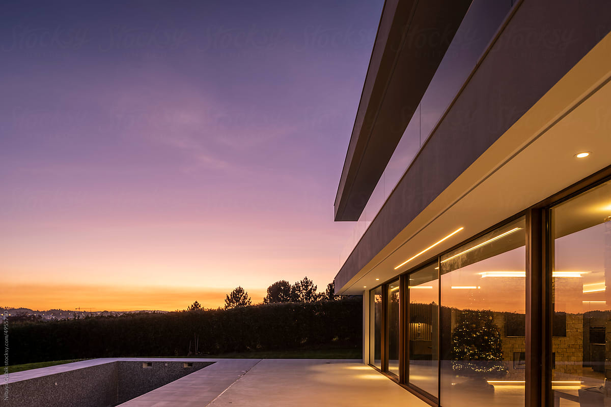 Modern residential family house facade with large windows at sunset