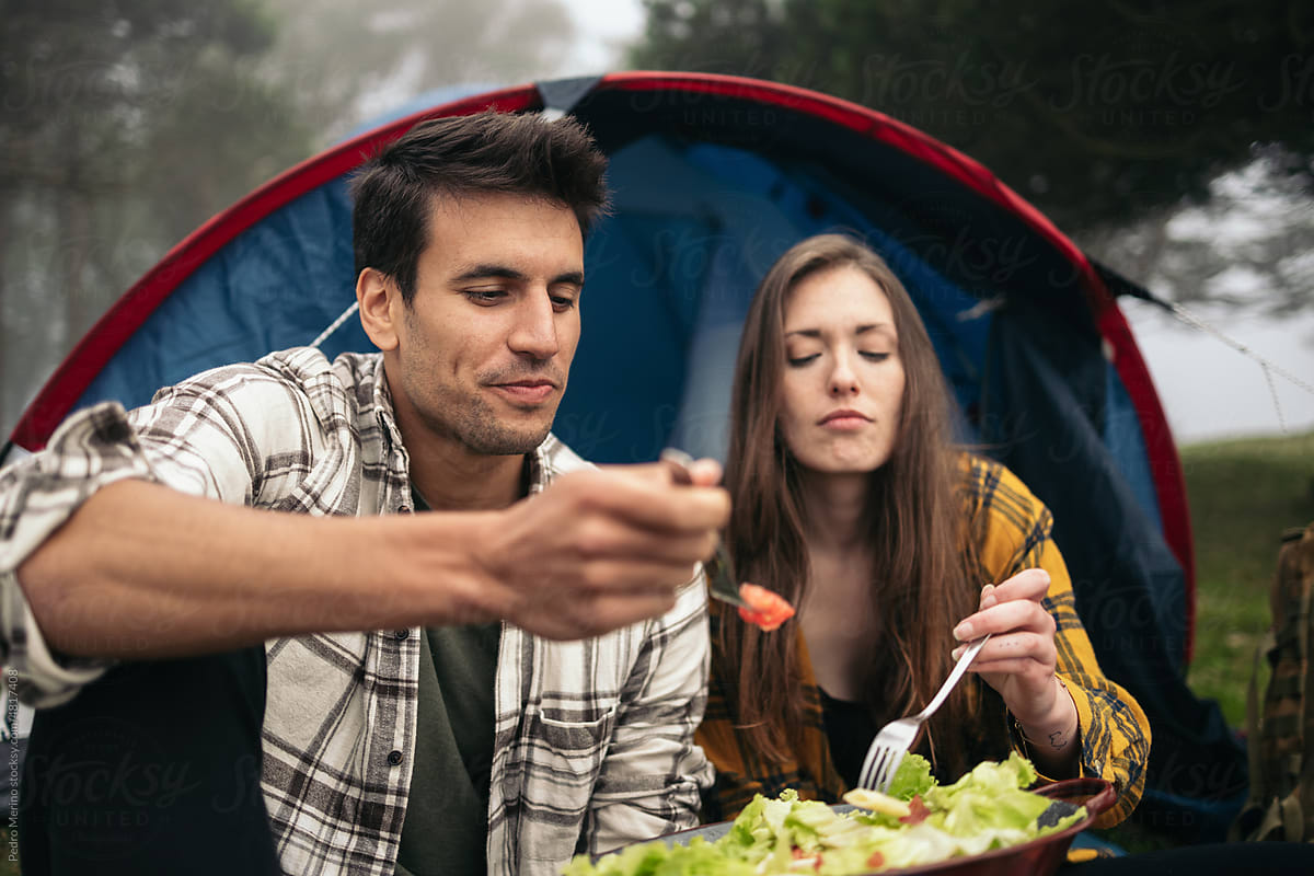 Couple eating outdoors while camping in the woods