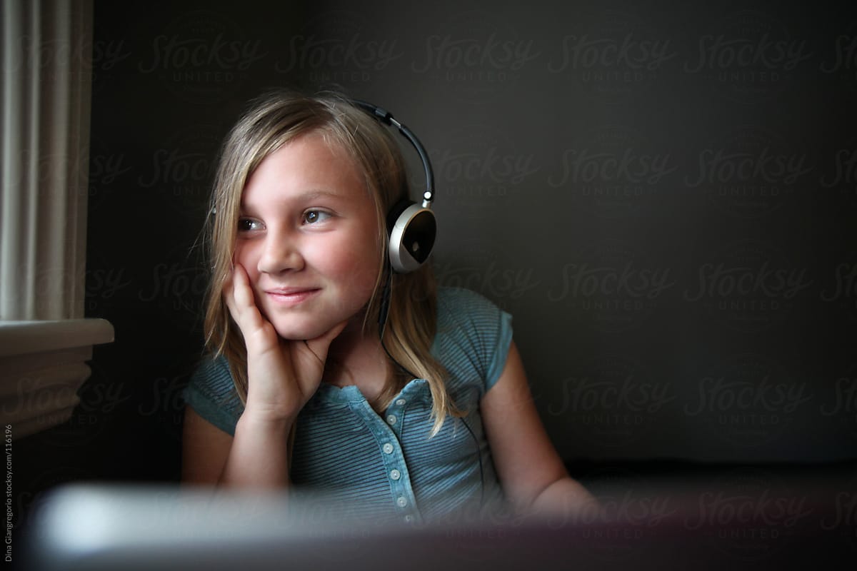 Young girl in bedroom using laptop and headphones