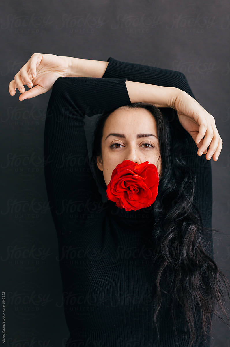 brunette woman with red roses in her mouth