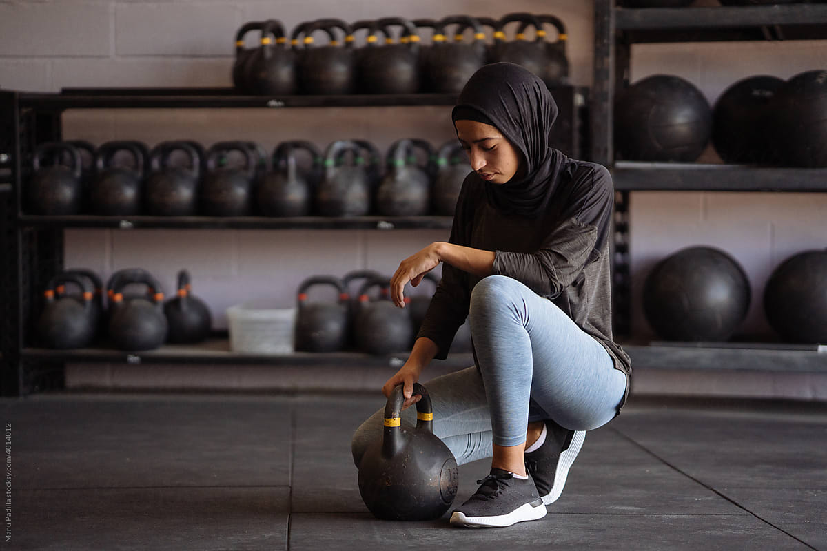 Sporty Muslim woman with kettlebell in gym