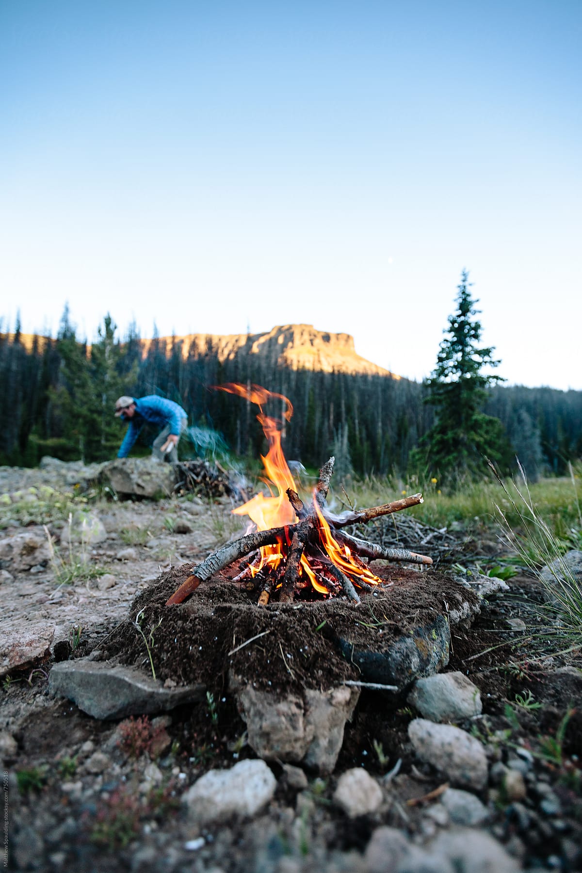 Man gathering wood and assembling small fire for camping
