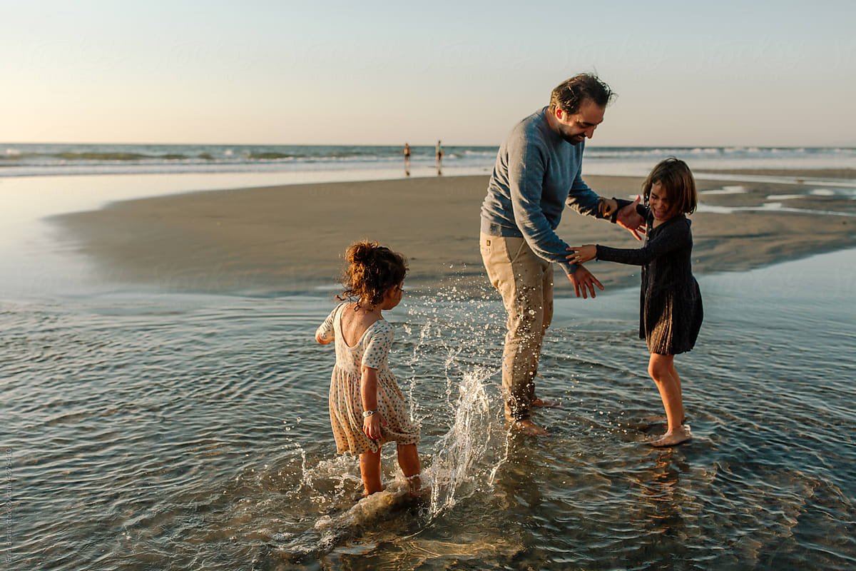 Happy father and daughters playing in ocean
