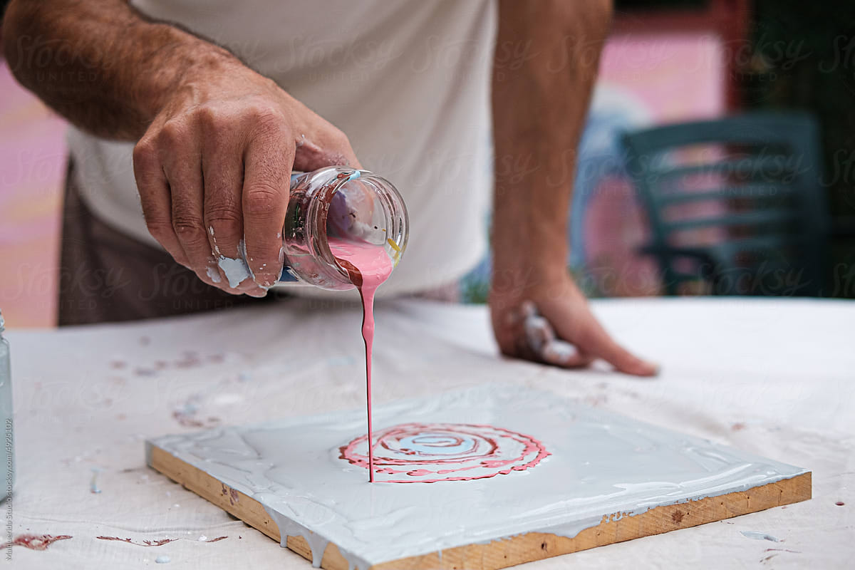 Artist man pouring paint on a picture