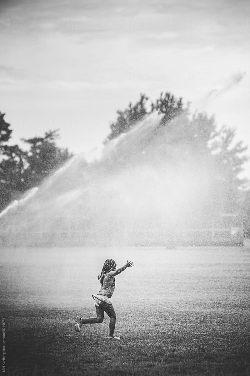 Girl running through sprinkler