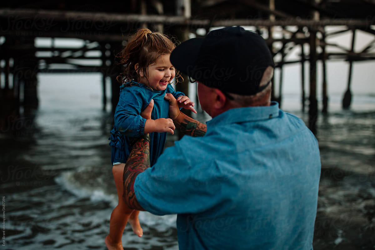 Dad holds up daughter near pier
