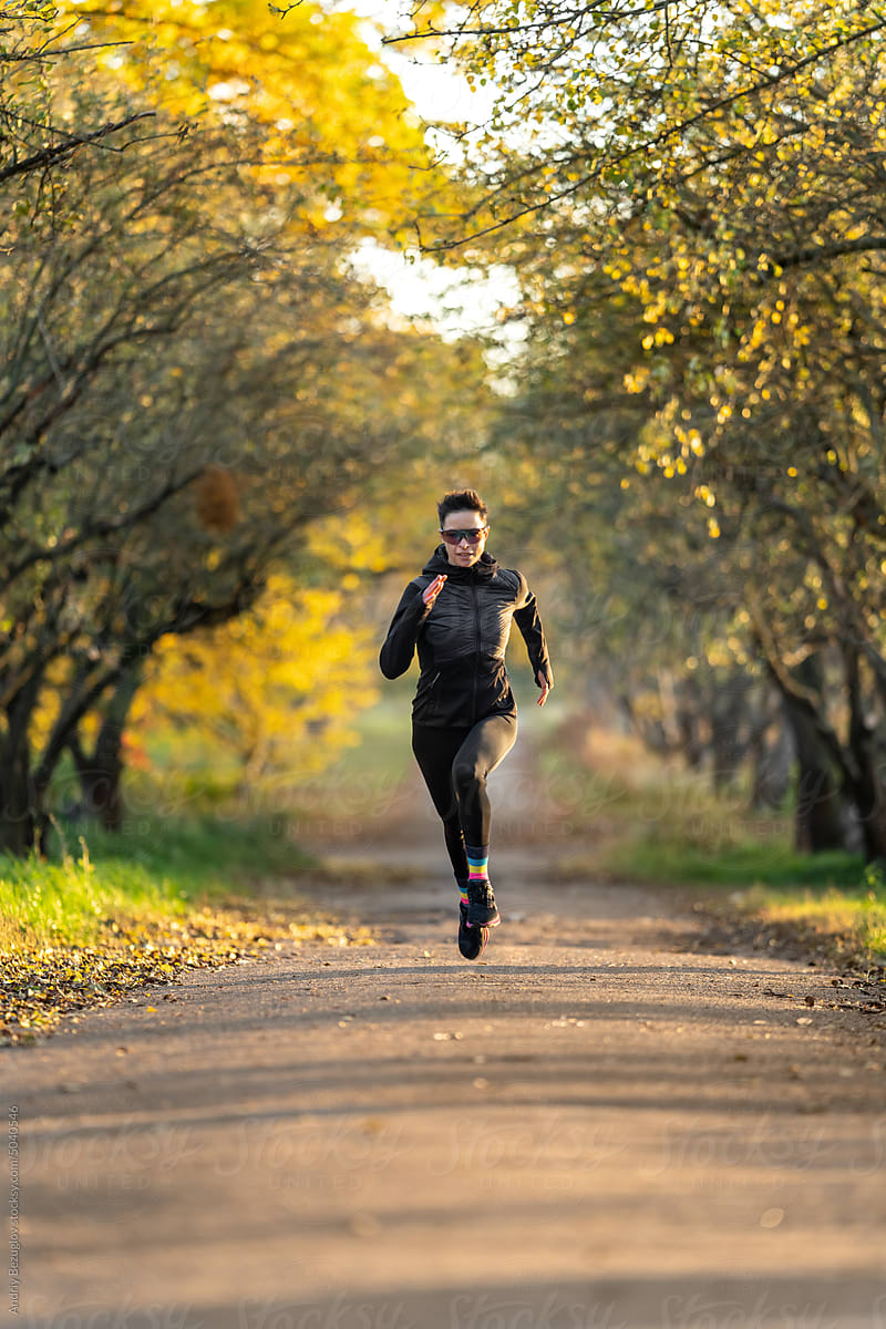 Sportive woman runs in colorful fall park
