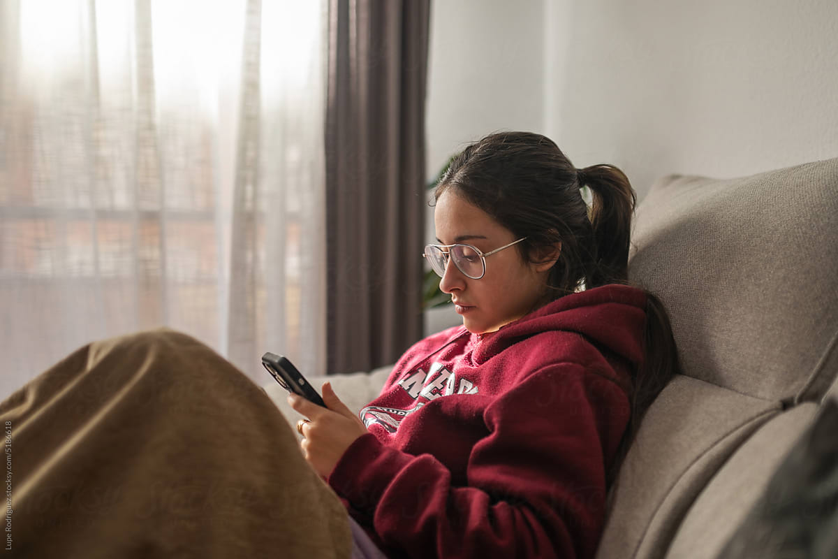 young teenage girl using mobile at home