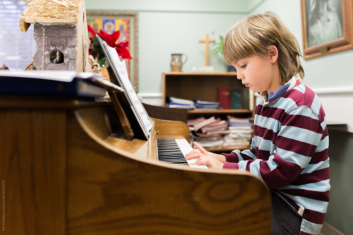 Boy playing piano in a reception room at Christmas time