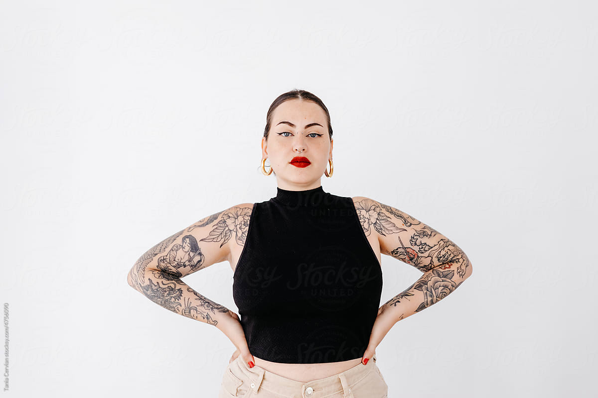Tattooed woman standing near wall