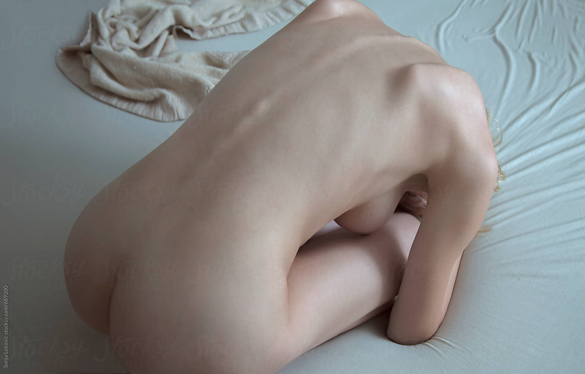 naked woman curled up on the bed