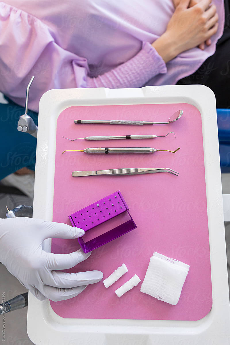 Dentist picking up dental instruments from a table