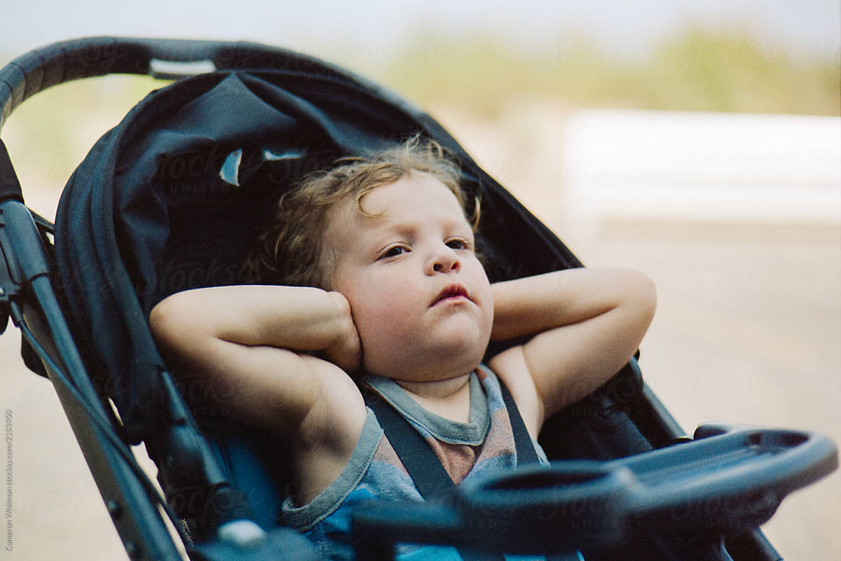 Toddler in stroller covering his ears