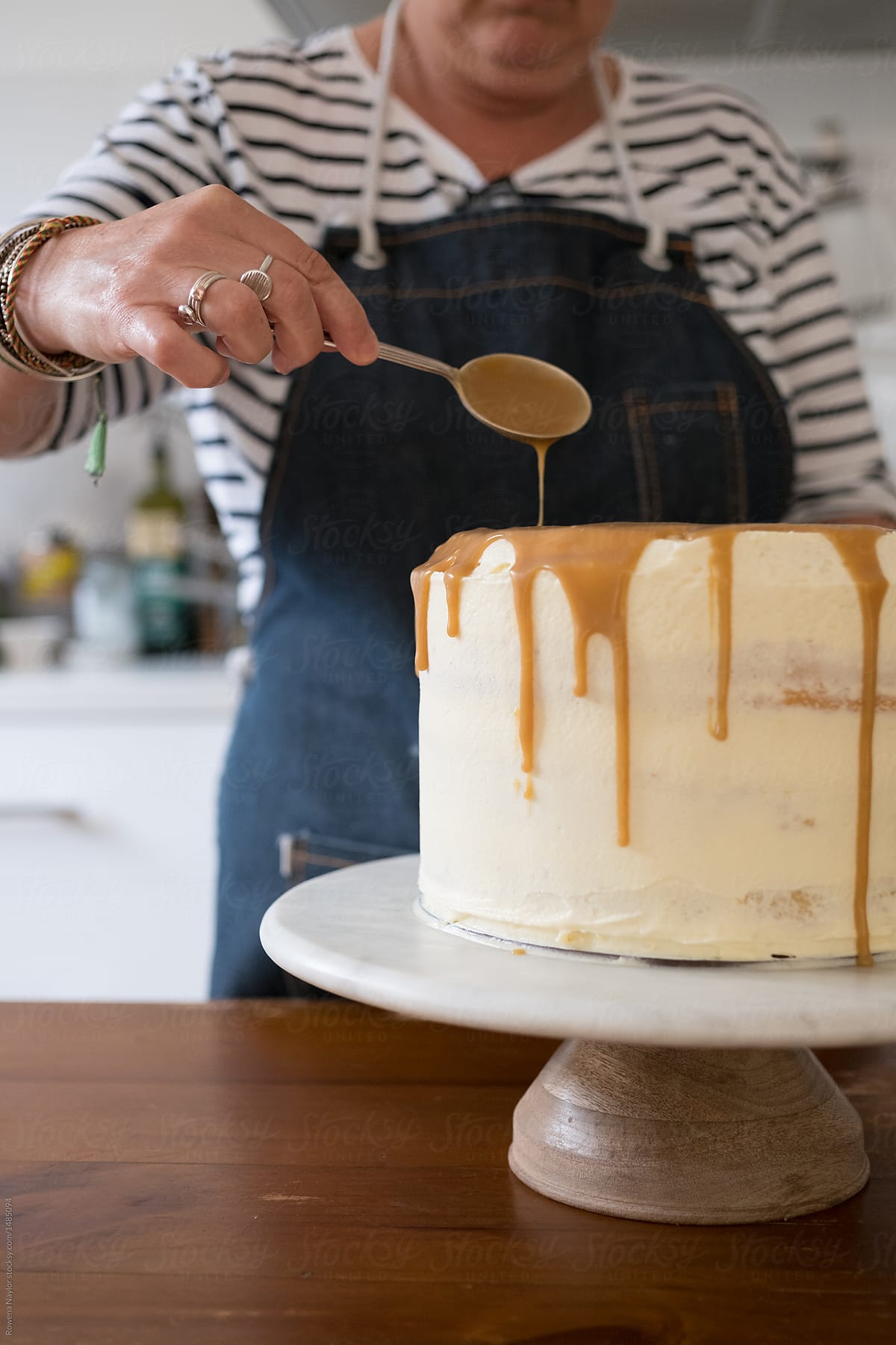 Home cook decorating a large cake with frosting and salted caramel