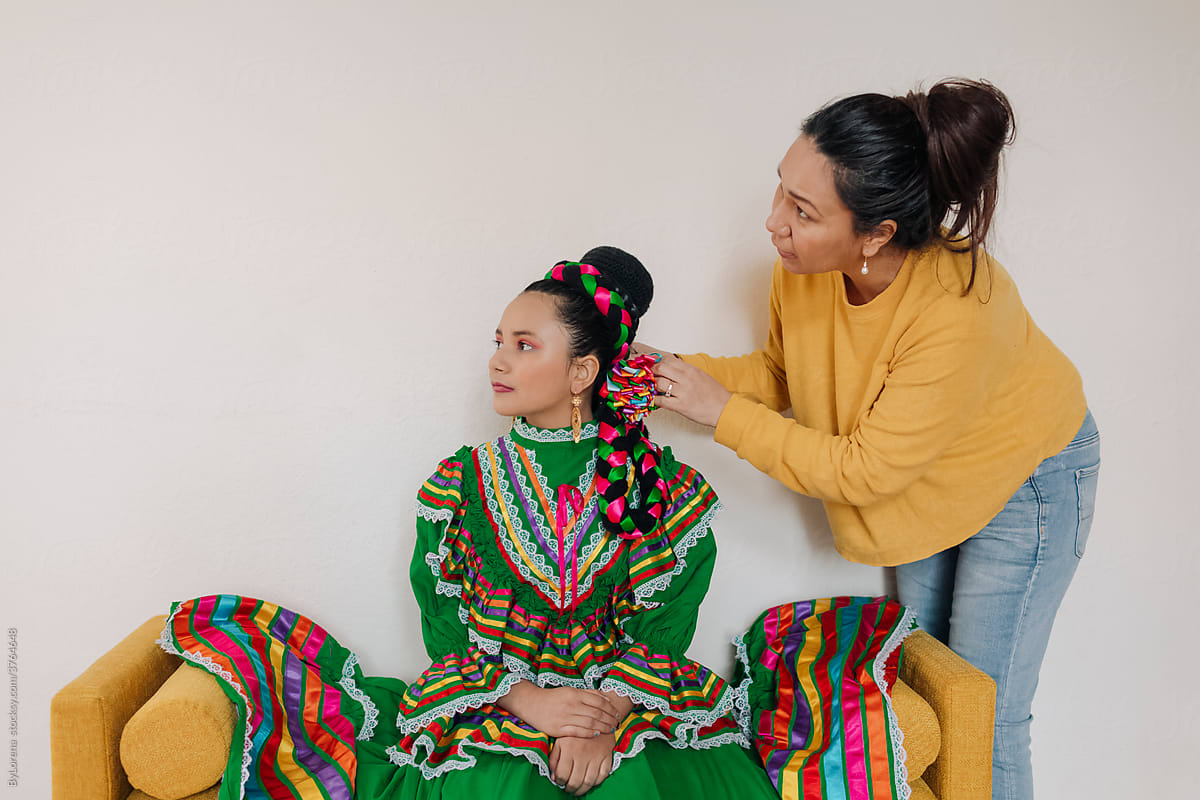 Mother helping daughter to put accessories on for a Mexican performance
