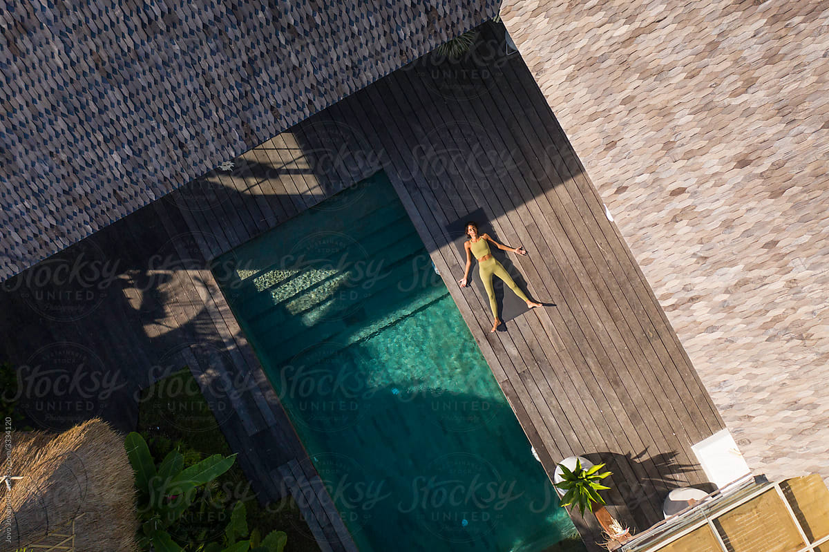 areal view of woman relaxing in corpse pose by the pool