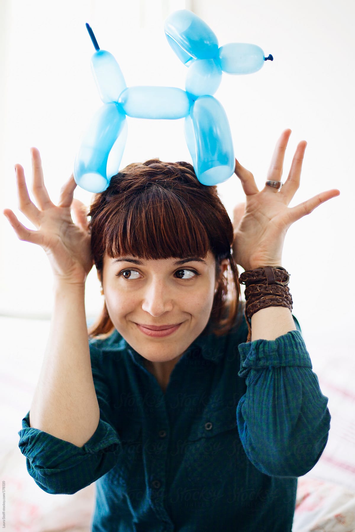 Beautiful smiling woman with a fringe holding on her head a balloon dog