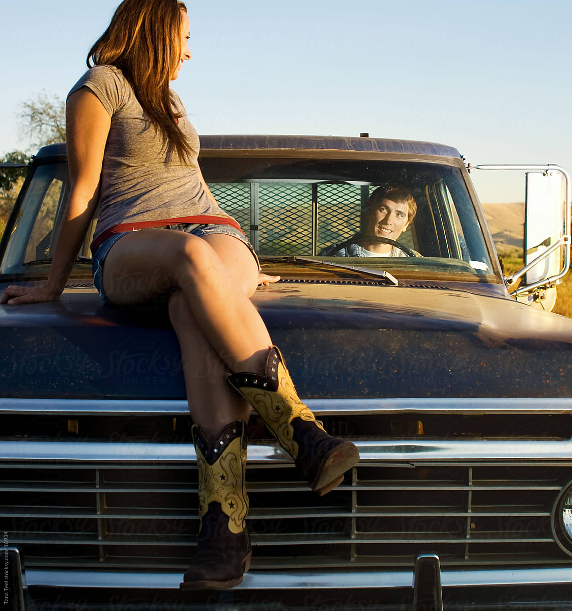 Young woman sitting on hood of old pickup