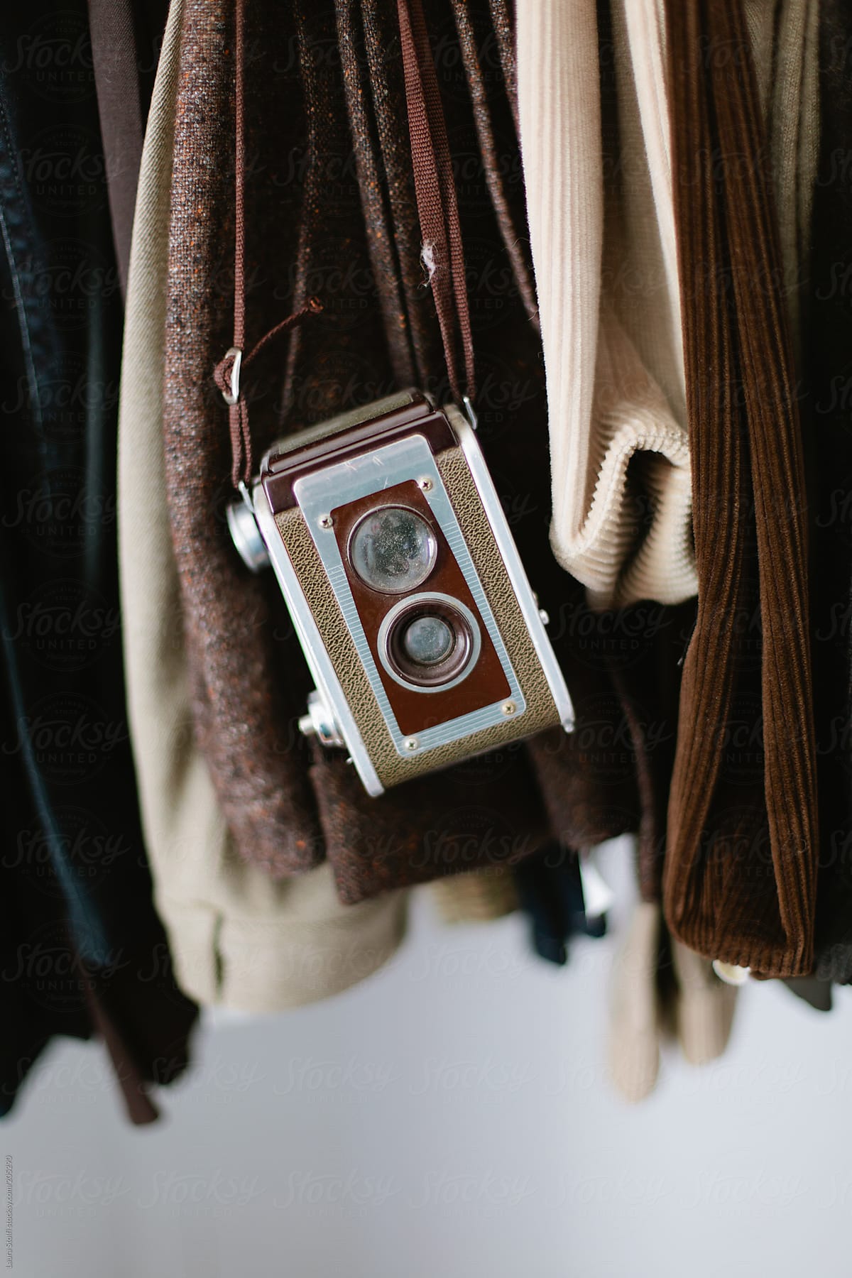 Old medium-format twin lens reflex camera hung amongst clothes in closet