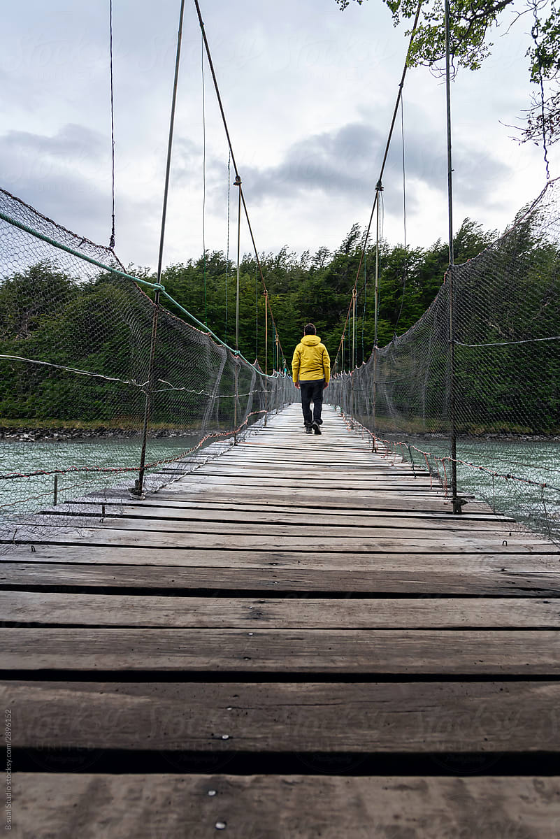 A mountaineer walking over a wooden hanging bridge
