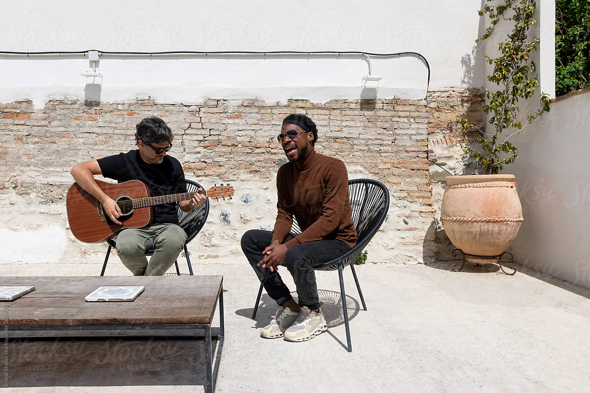 Diverse men creating music on terrace