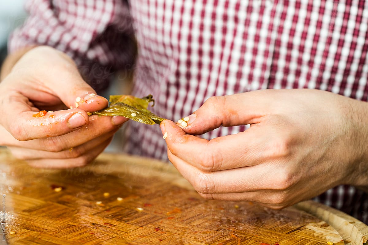 Man’s hands peeling skin off roasted chilies