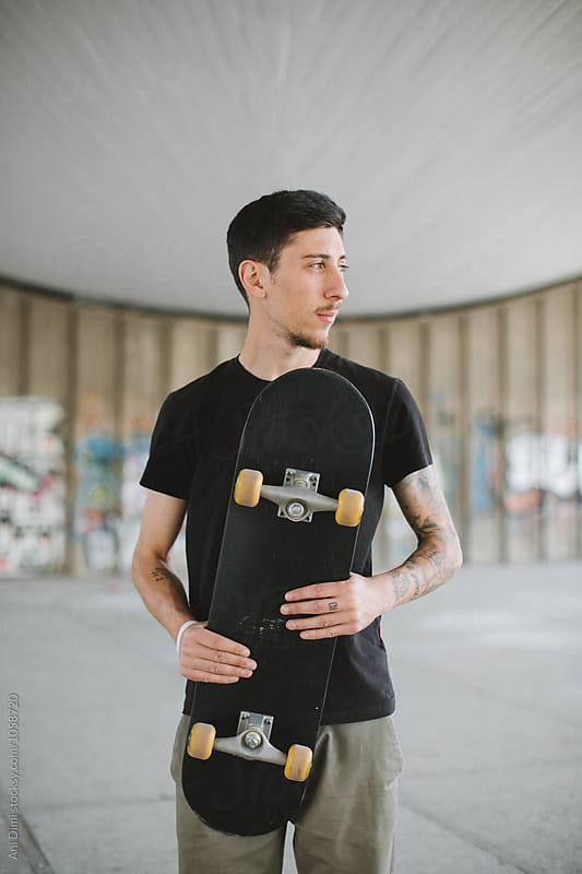 Portrait of man holding his skateboard