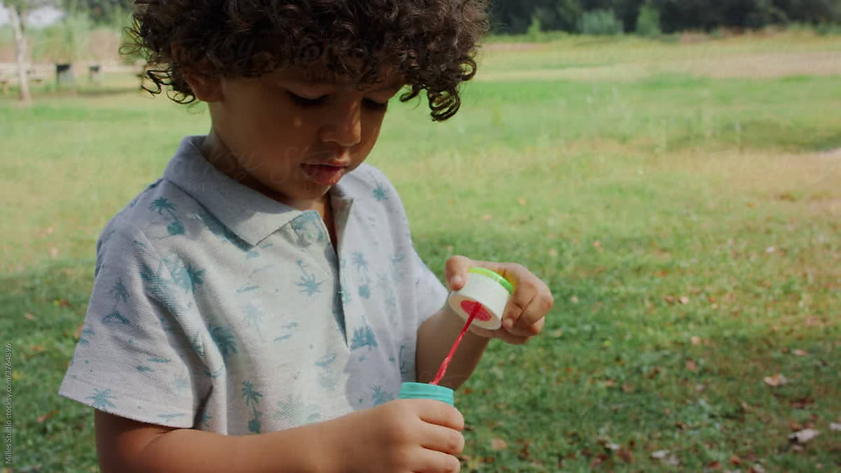 Hispanic Boy Blowing Bubbles On Lawn by Milles Studio