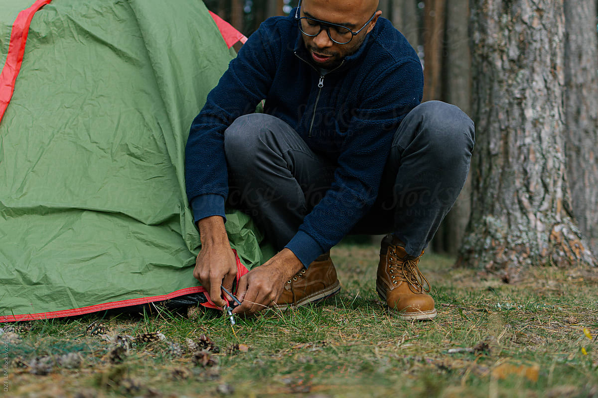 A man sets up a tent in the forest