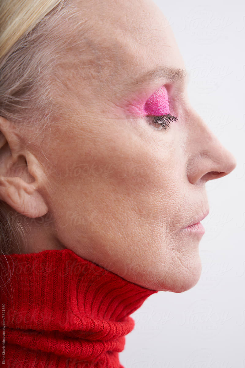 Portrait of an older woman in a red turtleneck on a white background
