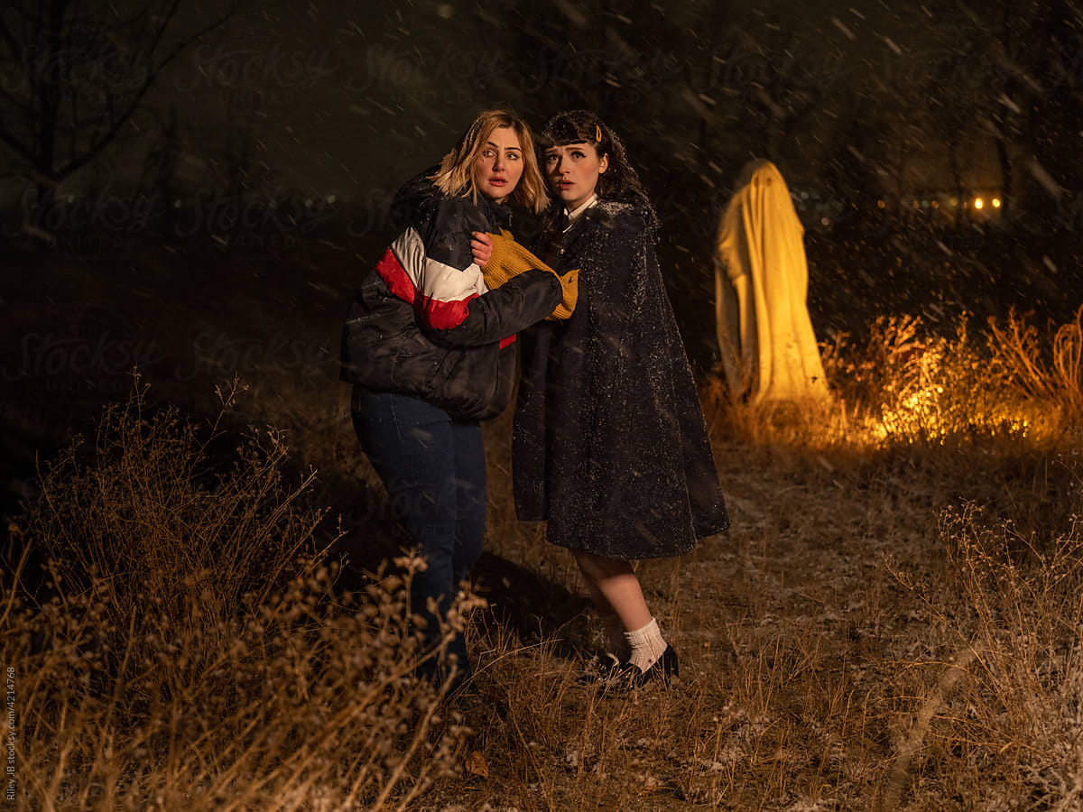 Two scared women with a ghost in background