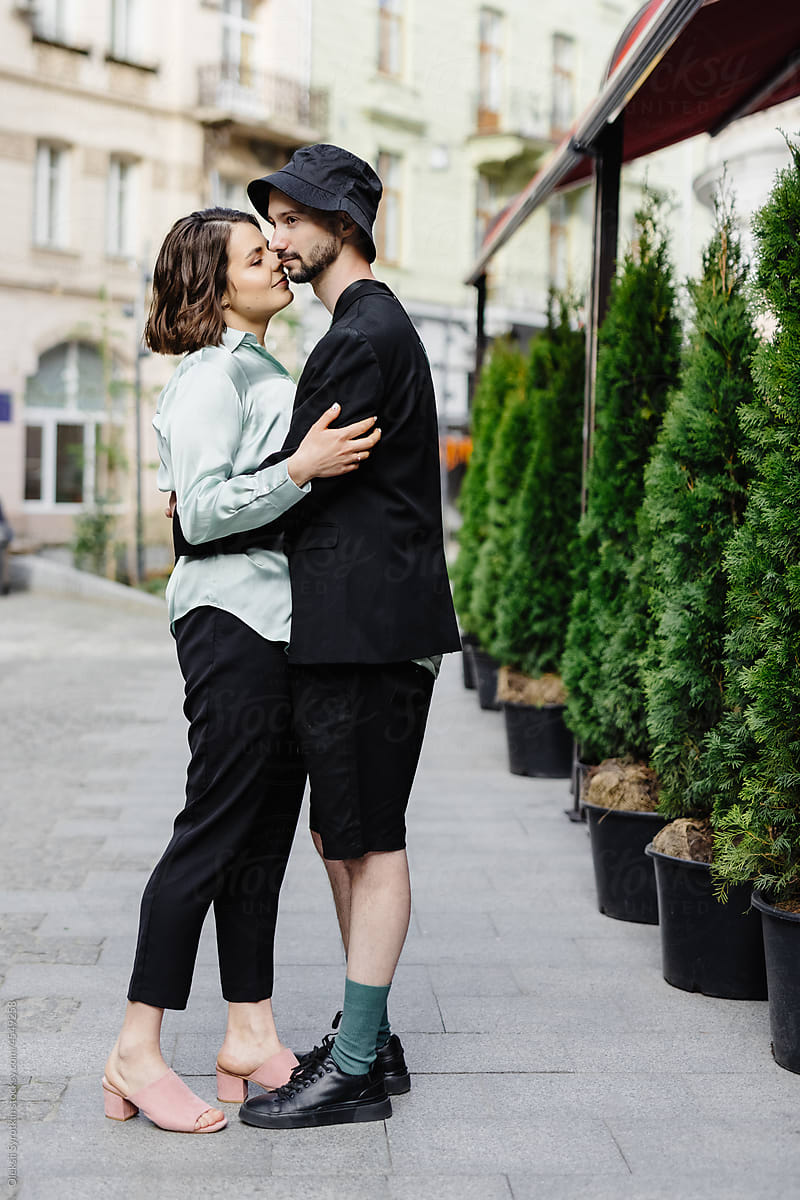 Boyfriend and girlfriend in casual outfits hugging on lane of city