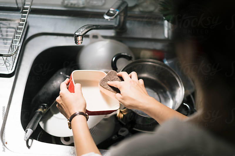 Asian young woman washing dishes in the sink