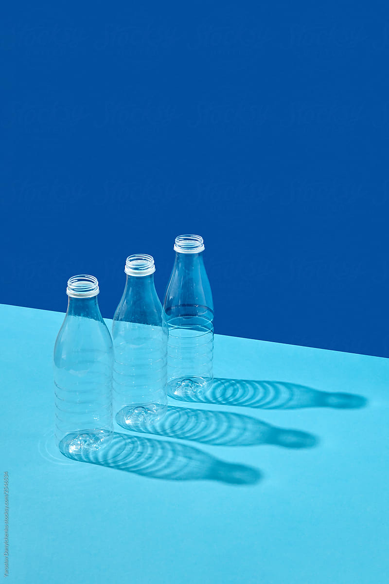 Plastic bottles on a double blue background with reflection of shadows