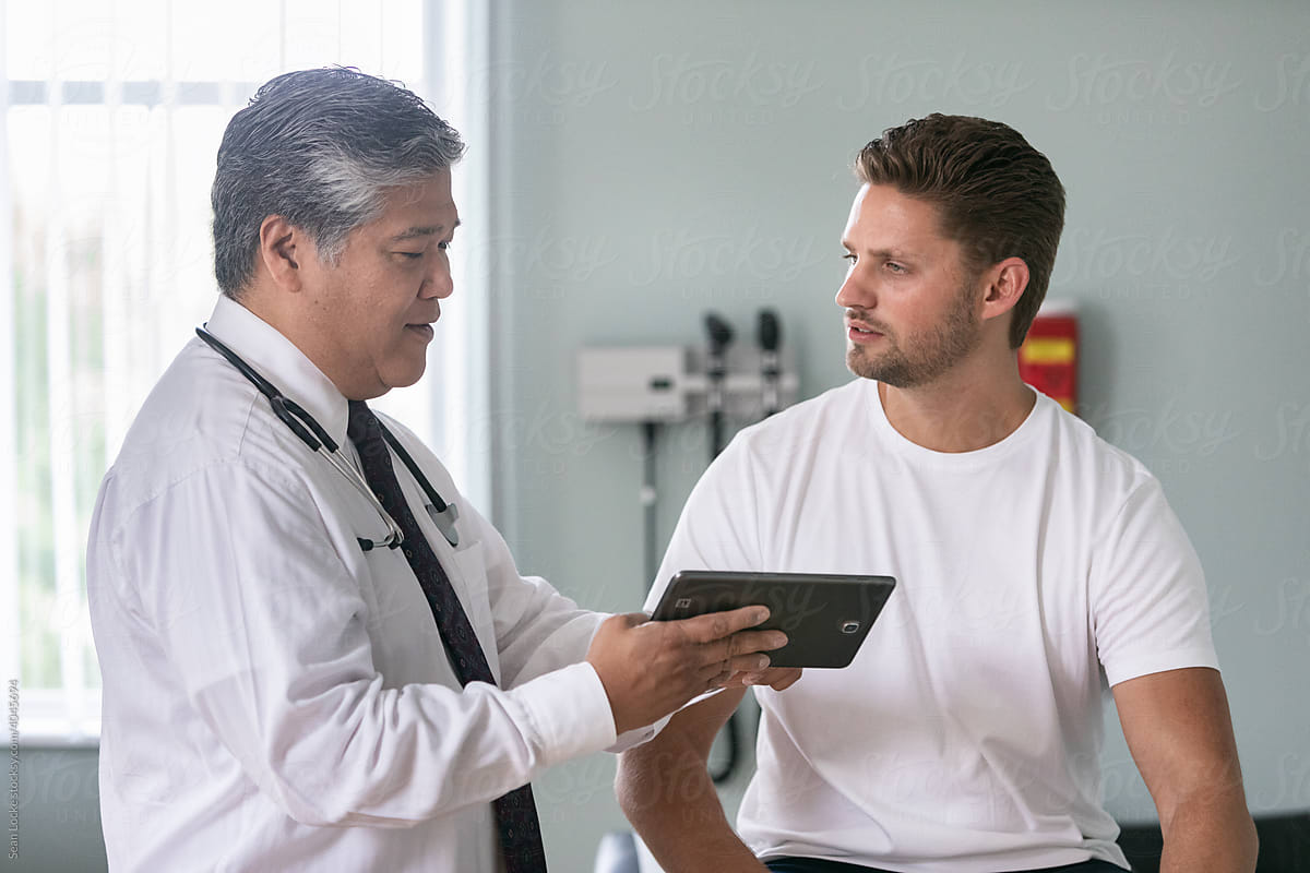 Exam: Doctor And Man Look At Digital Tablet