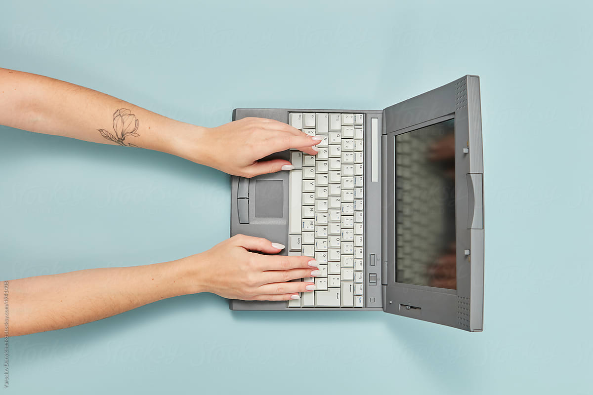 90s laptop with hands of working woman.