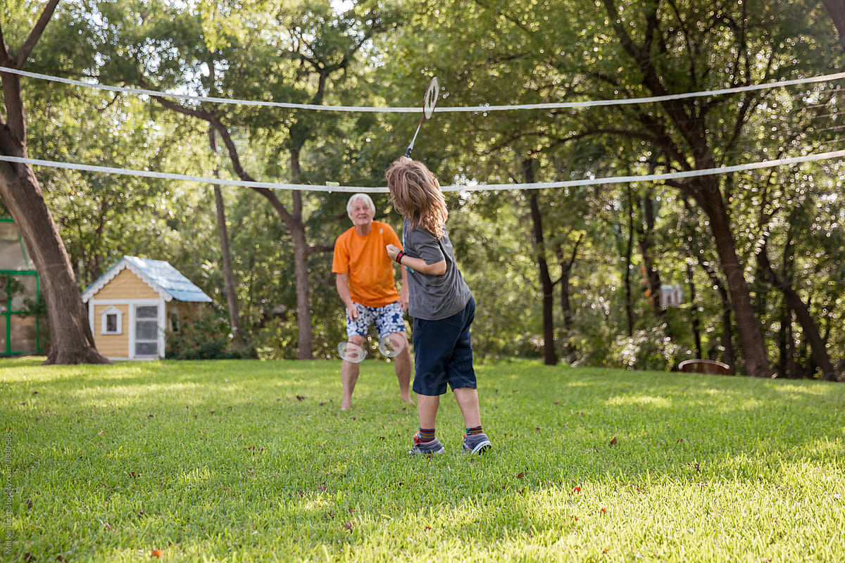 Grandpa and grandson play badmitton in backyard