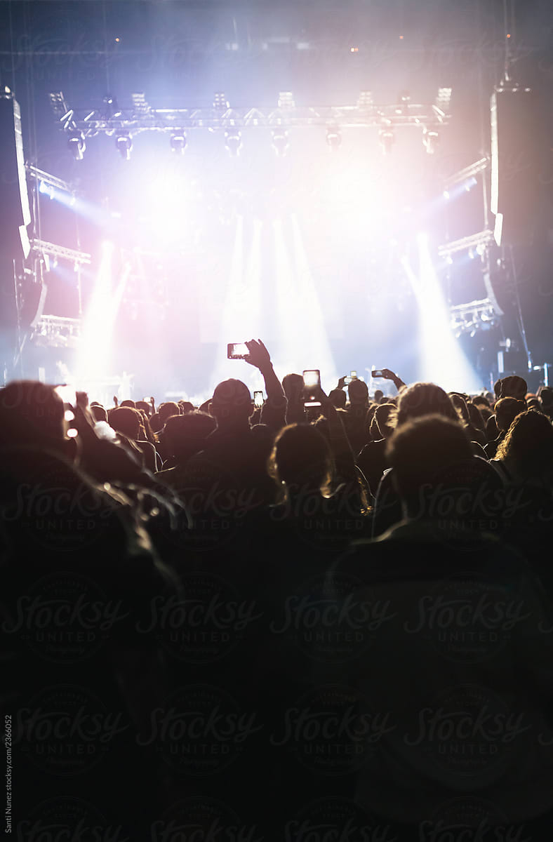 Silhouettes of concert crowd in front of bright stage lights